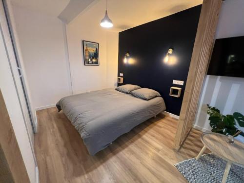 een slaapkamer met een bed en een zwarte muur bij Studio 1 - Mi-Côte - Studio à Orvault in Orvault