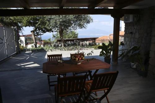 una mesa de madera con sillas y un bol de fruta. en Villa Serena, en Vico Equense
