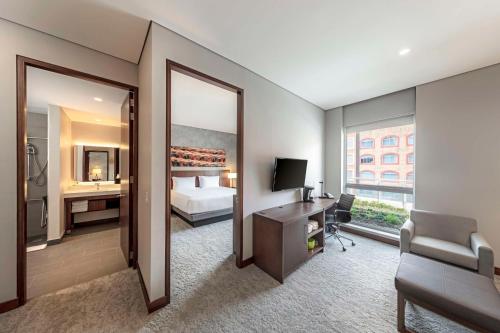 a hotel room with a bed and a desk and a mirror at Hyatt Place Bogota Convention Center in Bogotá