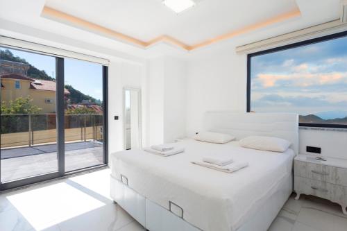 a white bedroom with a large white bed and large windows at Villa Sherbella in Fethiye