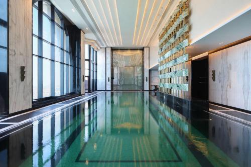 a swimming pool in a building with windows at Waldorf Astoria Doha West Bay in Doha