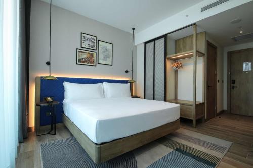 a bedroom with a large white bed with a blue headboard at Hilton Garden Inn Ankara Dikmen in Ankara