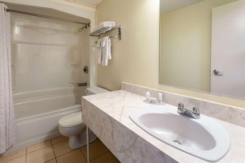 La salle de bains est pourvue d'un lavabo, d'une baignoire et de toilettes. dans l'établissement Travelodge by Wyndham Amherst, à Amherst