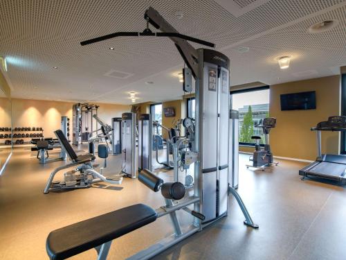 a gym with several tread machines in a room at Mercure Zürich City in Zürich