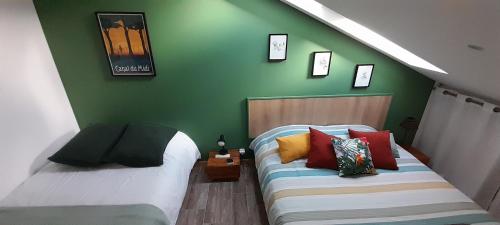 a bedroom with two beds and a green wall at La pause sous le pin B&B Chambres d'hôtes in Capestang