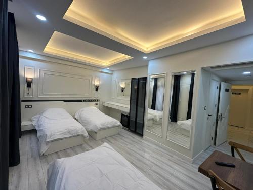 a bedroom with two beds and a desk and mirrors at Mitra otel in Diyarbakır