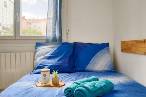- un lit avec des oreillers bleus et un plateau dans l'établissement Studio Cosy proche de Tête d'Or, à Villeurbanne