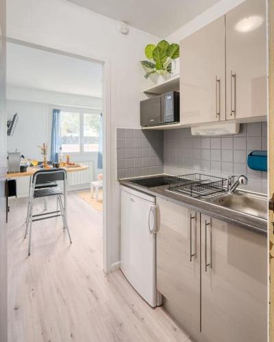 - une cuisine avec des placards blancs, un évier et une table dans l'établissement Studio Cosy proche de Tête d'Or, à Villeurbanne