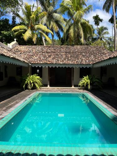 - une piscine en face d'une maison avec des palmiers dans l'établissement The Retreat Weligama, à Weligama