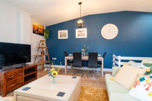 a living room with a table and a clock on the wall at The Old Mill Cottage in Fakenham