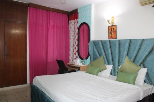 um quarto com uma cama grande com cortinas cor-de-rosa e azul em Awasthi Kozi Stays B&B - closest to VFS em Nova Deli