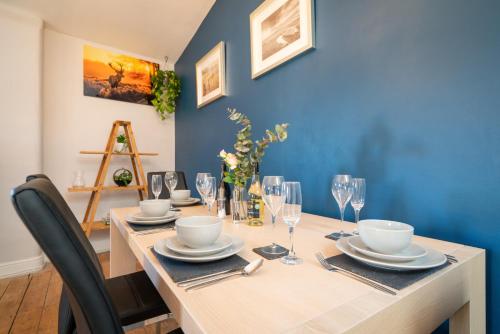 a dining room table with plates and glasses on it at The Old Mill Cottage in Fakenham