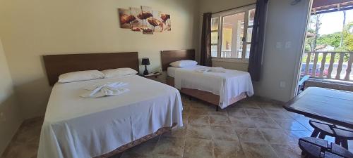a hotel room with two beds and a balcony at Pousada Pau Brasil in Guapimirim