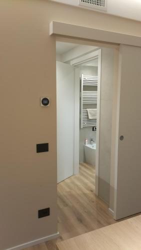 a hallway leading into a bathroom with white walls at fragilerooms in Dolo