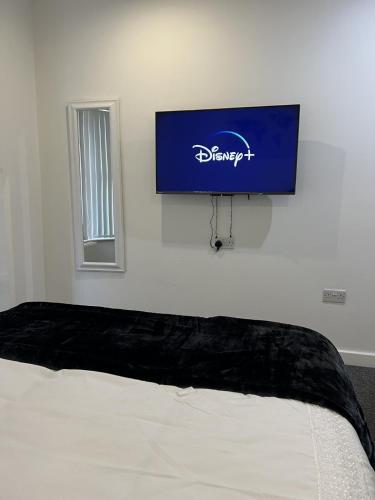 a flat screen tv on a wall above a bed at Room with King Size Bed and Private En suite Bathroom in the Centre in Watford