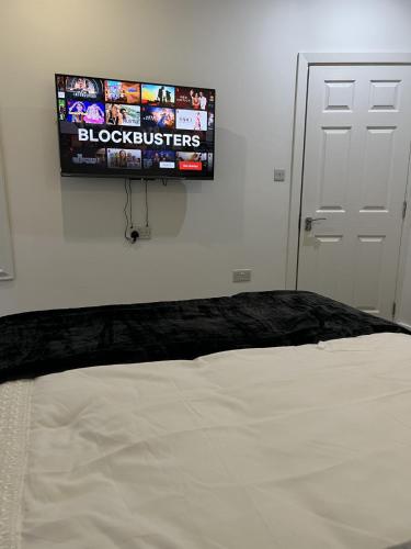 a flat screen tv on a wall above a bed at Room with King Size Bed and Private En suite Bathroom in the Centre in Watford