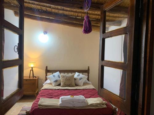 a bedroom with a bed with red sheets and windows at Hotel Cactus Plaza in Purmamarca