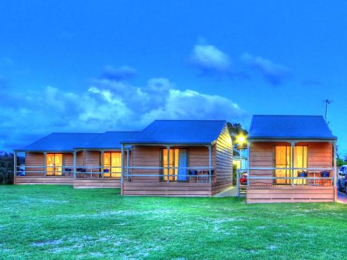 two wooden houses with blue roofs on a grass field at BIG4 Low Head Tourist Park in Low Head