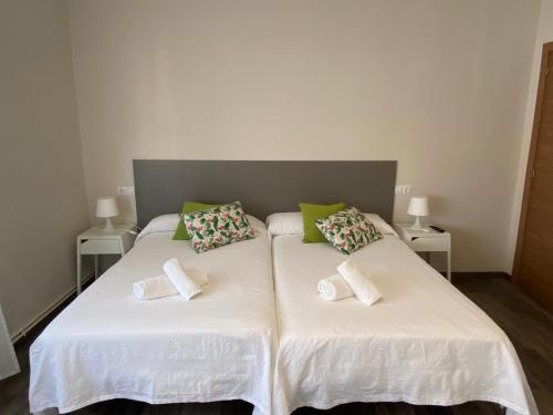 1 dormitorio con 2 camas con sábanas blancas y almohadas verdes en HOSPEDAJE STOP en Corrubedo