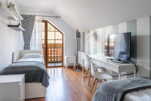 a bedroom with two beds and a desk with a television at Trevilles Apartamenty Mountain View in Szklarska Poręba