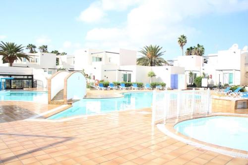 een zwembad van het resort met witte gebouwen en palmbomen bij Pachi Beach Alisios Playa Corralejo in Corralejo