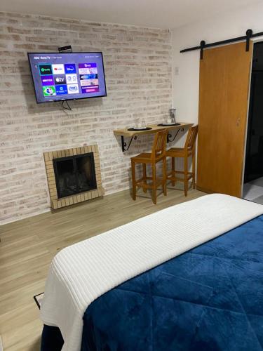 um quarto com uma cama e uma televisão numa parede de tijolos em Villagio da Mantiqueira em Monte Verde