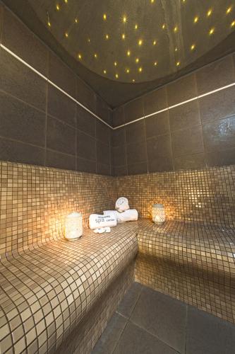 a bathroom with a tiled wall with towels at Vournelis Beach Hotel and Spa in Iraklitsa
