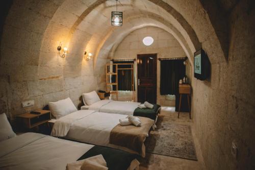 a room with three beds in a stone building at DAPHNE CAVE HOTEL in Avanos