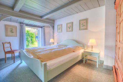 a bedroom with a bed and a chair and a window at Friesenhaus Sara S2 in Wenningstedt