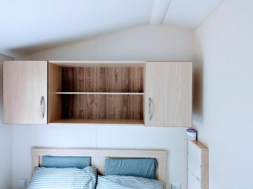 a bed in a small room with wooden cabinets at The Ocean Pearl caravan number 50 situated on the Cove holiday park in Southwell