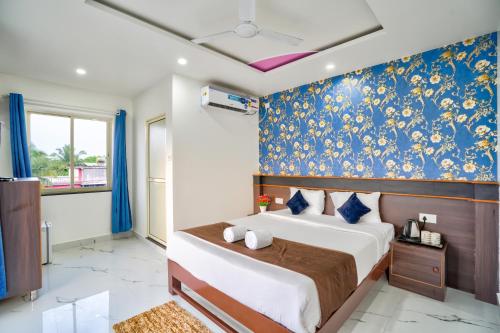 a bedroom with a bed with a blue and gold wallpaper at Hotel Antonio's Nr Calangute Beach in Calangute