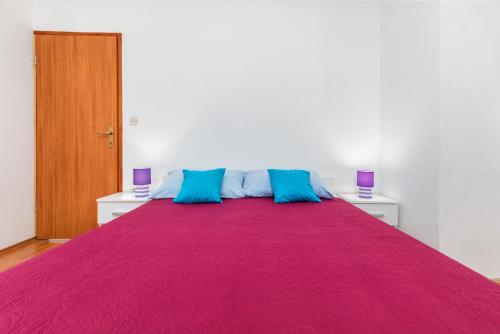 a large bed with purple and blue pillows on it at Center of Fažana Apartments Katarina in Fažana