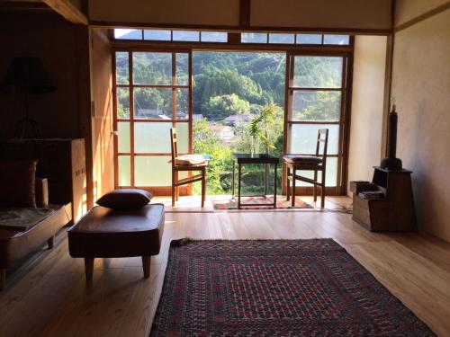 a living room with a large window and a rug at 朝食付き唐津里山の宿&ヨガ兎と亀 in Karatsu