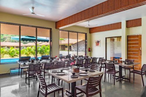 a dining room with tables and chairs and windows at CASA AMORA in Lonavala