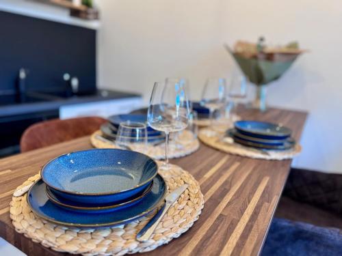 a wooden table with plates and wine glasses on it at Chaleureux T2 proche gare in Bourgoin