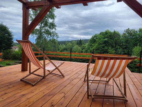 two chairs and a table on a wooden deck at Chatička na Cikánce in Svratka