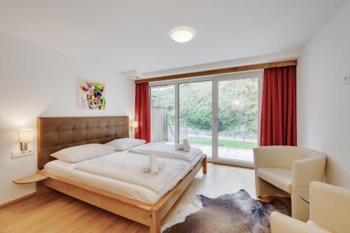 a bedroom with a bed and a large window at Alpin & See Resort - Pinzgau Holidays in Zell am See