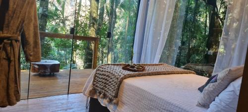 1 dormitorio con 1 cama frente a una ventana grande en TreeHouse Seu Paraíso nas Montanhas, en Marechal Floriano