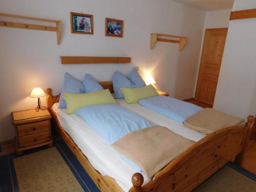 um quarto com uma grande cama de madeira com almofadas azuis em Holmbauer Ferienwohnung Panoramablick em Ober-Etrach
