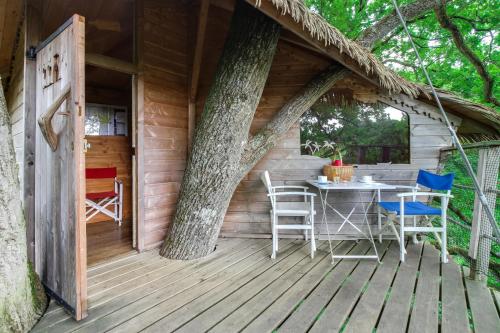 un porche de una casa en un árbol con mesa y sillas en Domaine des vaulx en La Baconnière