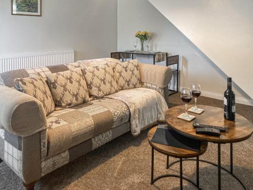 a living room with a couch and a table with wine glasses at Low Stonebank Cottage-uk41027 in Hunwick