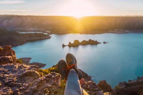 una persona sentada en la cima de una montaña viendo la puesta de sol en Departamentos Segovia., en San Rafael