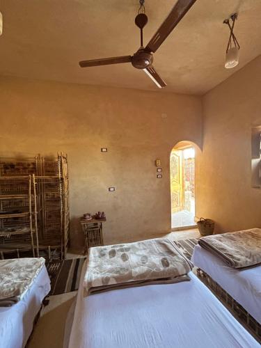 a bedroom with two beds and a ceiling fan at Agpeninshal Ecolodge in Siwa