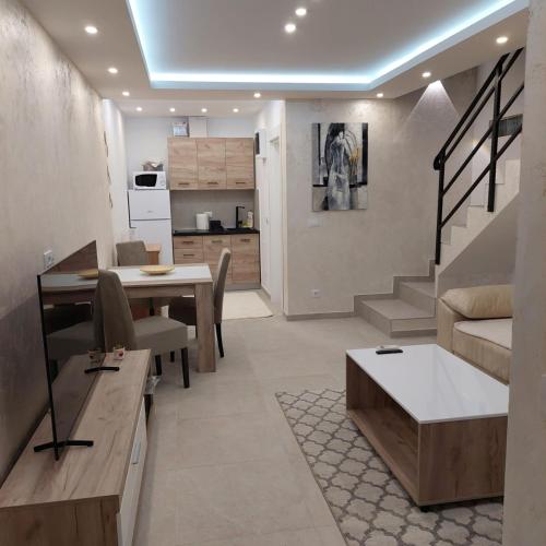 a living room with a dining table and a kitchen at Apartman LUX Jelena in Surčin