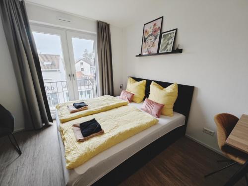 um quarto com uma cama com lençóis amarelos e uma janela em CASA FRIDA-Zentral-Outlet-Aufzug-Stylisch-Unique em Metzingen