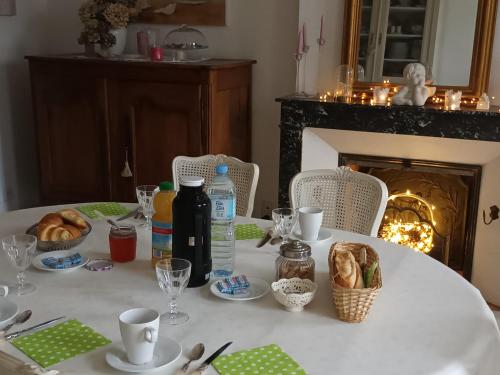 - une table avec une nappe blanche avec du pain et une cheminée dans l'établissement La chouett'chambre, à Les Hermites