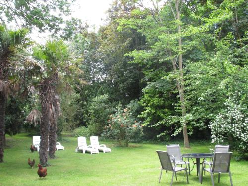 a table and chairs in a yard with chickens in the grass at Manoir de la Marjolaine in Cabourg