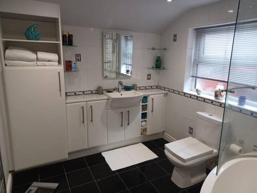 a white bathroom with a toilet and a sink at 7 Cromwell Gardens - 2 Bed House in Scarborough