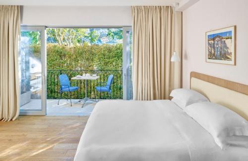 een slaapkamer met een bed en een balkon met een tafel en stoelen bij Auberge La Coste in Le Puy-Sainte-Réparade