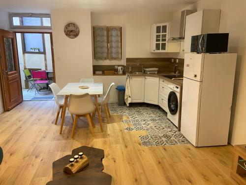 une cuisine avec une table et un réfrigérateur blanc dans l'établissement Charmant appartement, à Saint-Claude